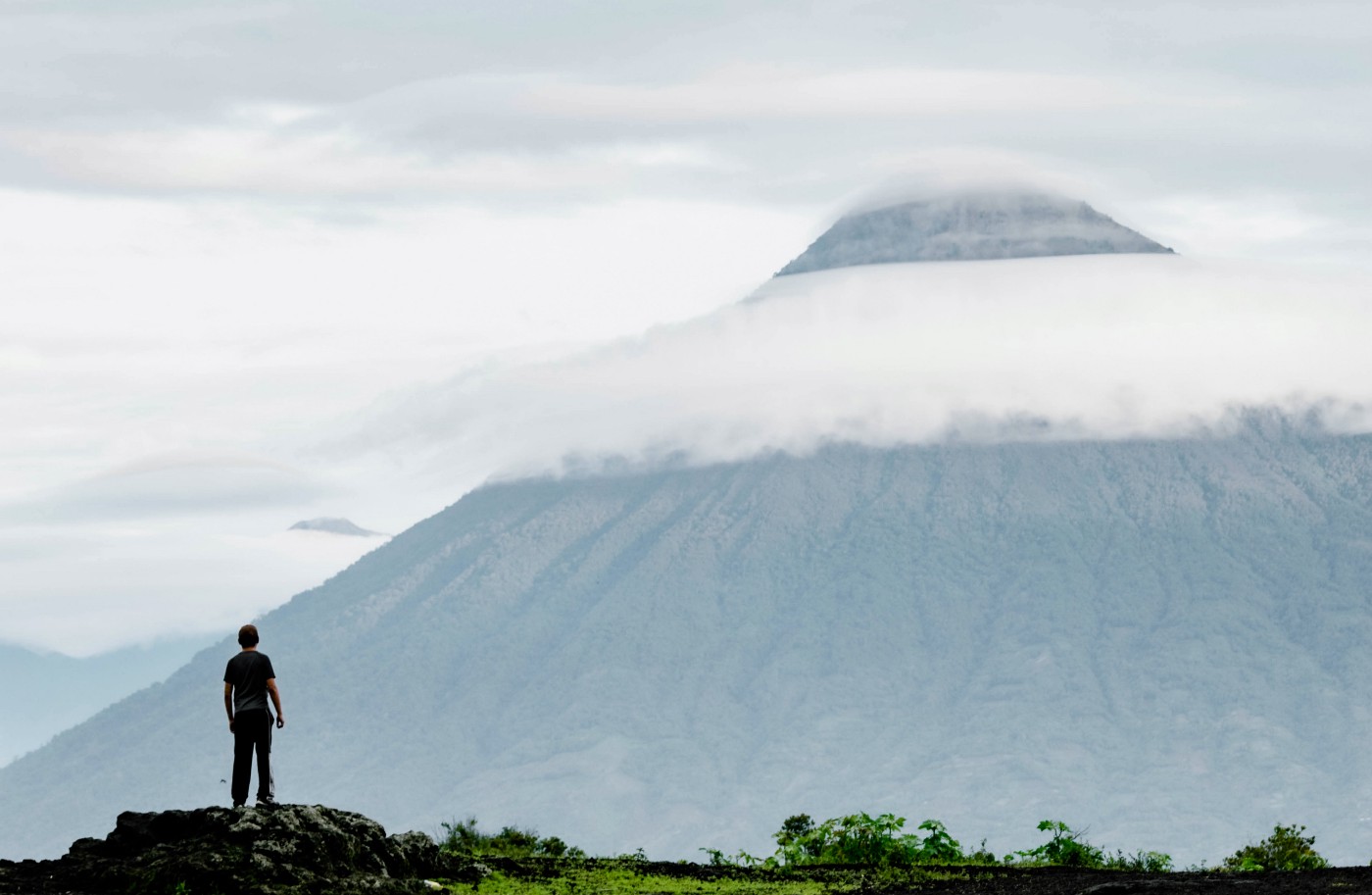 A man standing in front of a mountain. 